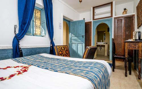 a bedroom with a bed and some blue curtains at Riad L'orange Bleue in Marrakesh