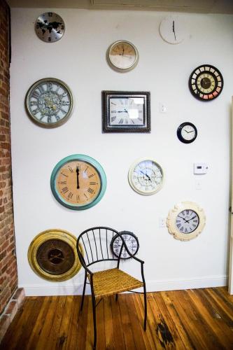 a wall with many different clocks on a wall at Hostel Fish in Denver