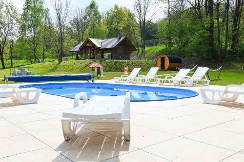 einen Pool mit Stühlen, einem Tisch und einem Pavillon in der Unterkunft Domki Łowisko Wieniec in Gdów