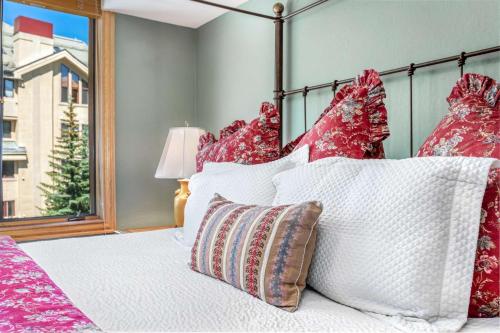 a bedroom with a bed with white pillows and a window at Beaver Creek Lodge 411 in Beaver Creek