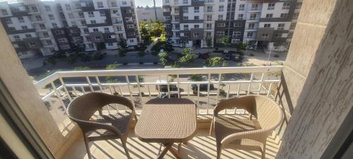 3 Stühle und ein Tisch auf einem Balkon mit Stadtblick in der Unterkunft Luxury apartment in Madinaty in the heart of new cairo in Madinaty