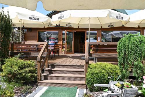 a restaurant with benches and tables and umbrellas at Domki Łowisko Wieniec in Gdów