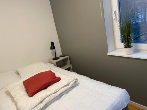 Una cama blanca con una almohada roja. en Fjällkåken en Idre