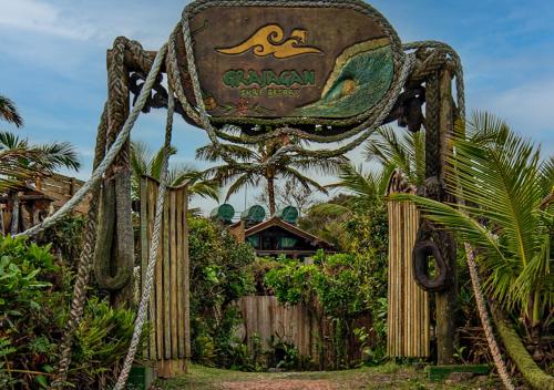 a sign for the caymanasyasyasy resort with a fence at Grajagan Surf Resort in Ilha do Mel