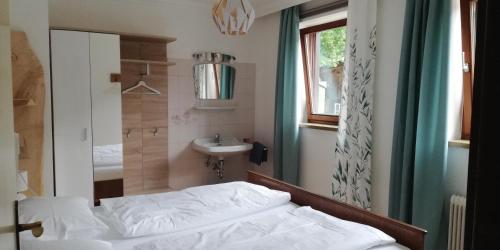 Schlafzimmer mit einem Bett, einem Waschbecken und einem Spiegel in der Unterkunft Abenteuerhof in Weißenbach