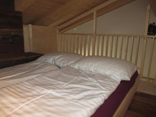 a bed with white sheets and pillows in a room at Abenteuerhof in Weißenbach