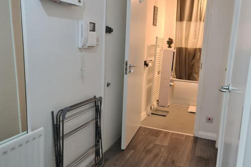 a hallway with a white room with a door and a bathroom at Stylish room kingsize bed 1 stop from Wembley stadium in Wealdstone