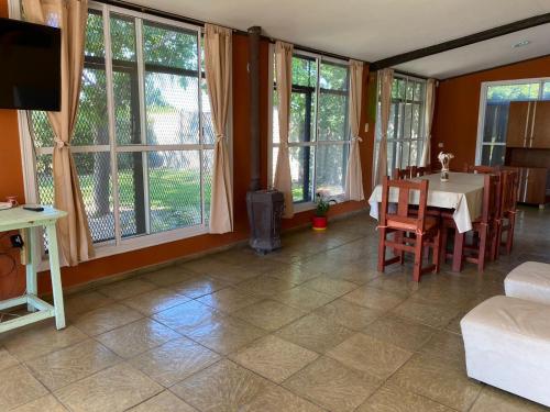 sala de estar con mesa, sillas y ventanas en Casa Quinta Buen Descanso en San Pedro
