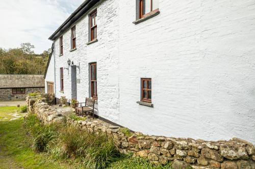 a white building with windows and a stone wall at Aberfforest House in Newport