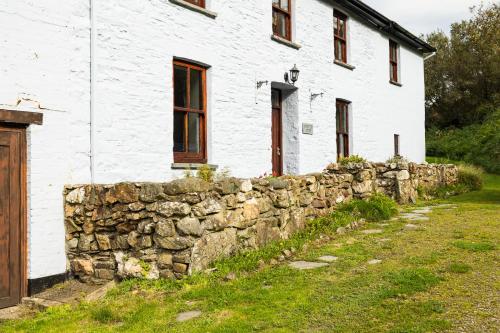 an old stone wall in front of a white building at Aberfforest House in Newport