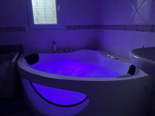 bagno con vasca viola e lavandino di Suite Jacuzzi-Cinéma a Les Clayes-sous-Bois