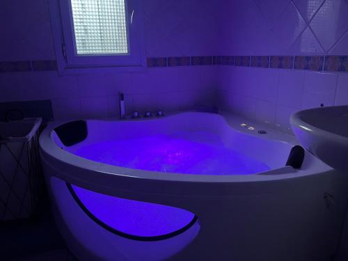 a bathroom with a purple bath tub with a sink at Suite Jacuzzi-Cinéma in Les Clayes-sous-Bois