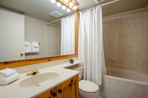 a bathroom with a sink and a toilet and a mirror at Spacious Benchlands Chalet by Harmony Whistler in Whistler