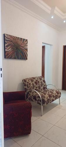 un salon avec une chaise et un tableau mural dans l'établissement LM Home, à Governador Valadares