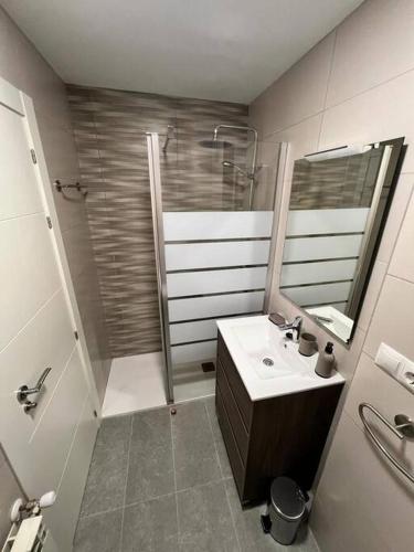 een badkamer met een wastafel, een douche en een spiegel bij Apartamento acogedor in Santander