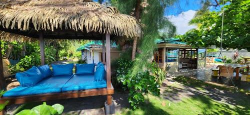 un sofá azul bajo una cabaña de paja en un patio en Villa Coco Lagoon en Punaauia