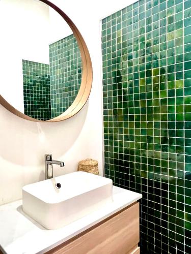 une salle de bain carrelée verte avec un lavabo et un miroir dans l'établissement Casa Mandulina - Plein cœur du Quartier Préfecture, à Marseille