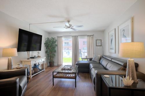 a living room with a couch and a tv at Fully Updated, Ground Floor, Poolside With Great Ocean View - Unit 49! in Cocoa Beach