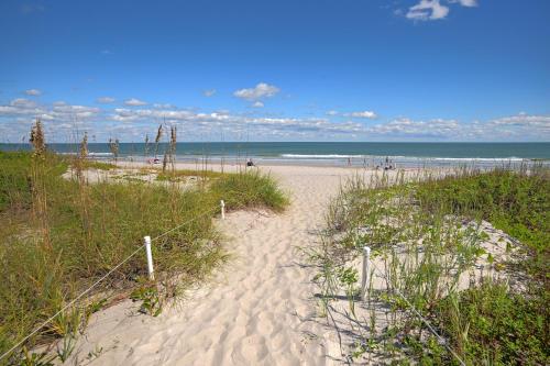 a sandy beach with a fence and the ocean at Fully Updated, Ground Floor, Poolside With Great Ocean View - Unit 49! in Cocoa Beach