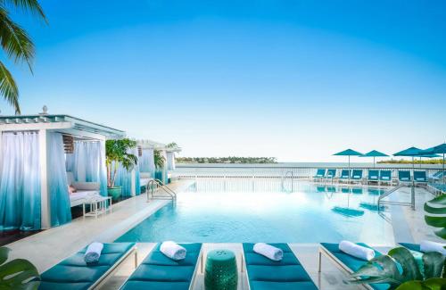 a swimming pool with blue furniture and a view of the ocean at Ocean Key Resort & Spa, a Noble House Resort in Key West