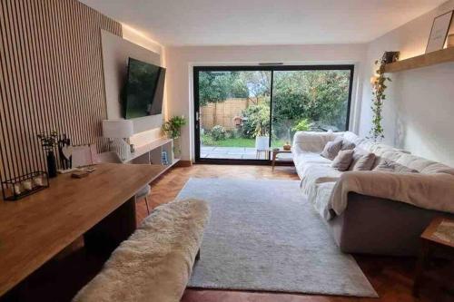 a living room with a large couch and a large window at Pretty fancy staycation - South East London / Kent in Bromley