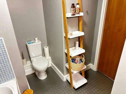 a small bathroom with a white toilet and shelves at Luxury Two Bedroom En-Suité Apartment in Manchester