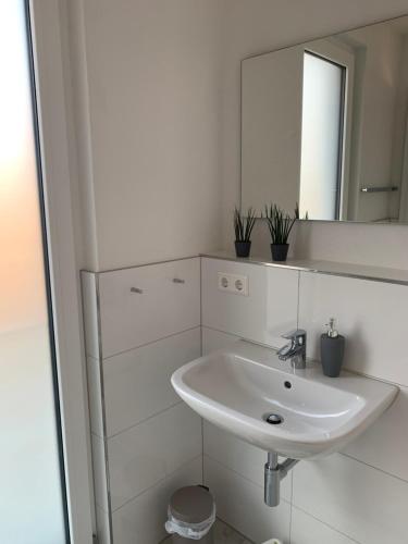 La salle de bains blanche est pourvue d'un lavabo et d'un miroir. dans l'établissement Wohnung in Reutlingen, à Reutlingen