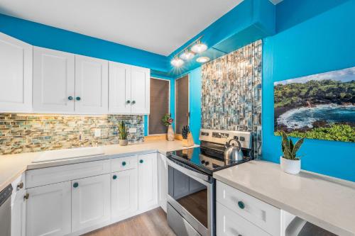 a kitchen with white cabinets and blue walls at Eldorado L102 in Kahana