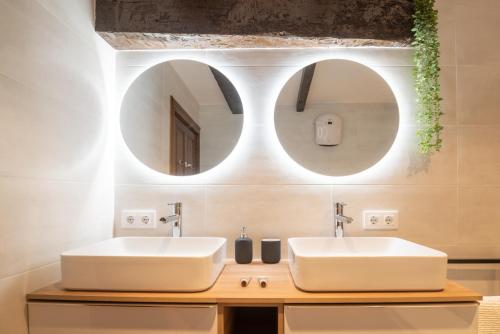 a bathroom with two sinks and two mirrors at Apto histórico en el centro, a 2 min de la playa in Llanes