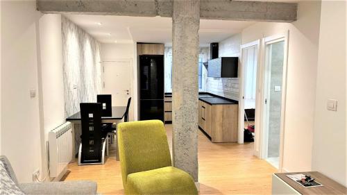 a living room with a green chair and a kitchen at Bonito Apartamento en Zamakola in Bilbao