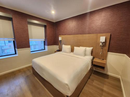 a bedroom with a large bed and two windows at The Mayfair Hotel Times Square, an Ascend Collection in New York