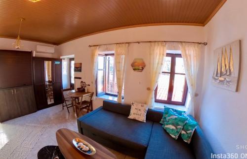 ein Wohnzimmer mit einem blauen Sofa und einigen Fenstern in der Unterkunft Sun Oniro Studio in Samothráki