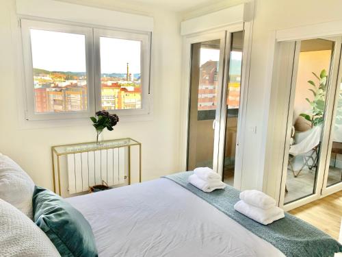 1 dormitorio con 2 toallas en una cama con ventanas en El Pisín de Avilés. Parking / WIFI, en Avilés