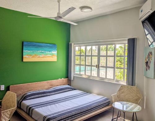 a green bedroom with a bed and a window at Walkable Rinconada Studio King Bed, Pool, Fast WiFi - Trees in Puerto Escondido
