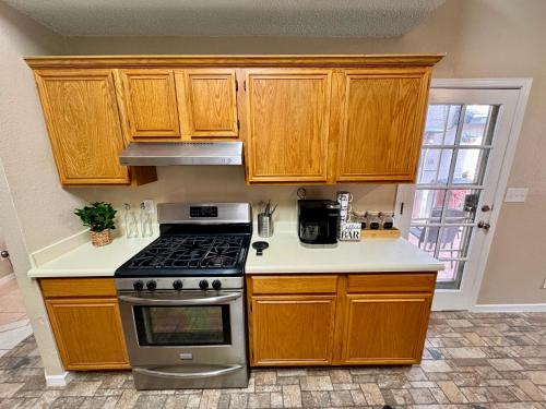 uma cozinha com armários de madeira e um forno com placa de fogão em Peaceful West: 4BR Dusk Haven em El Paso