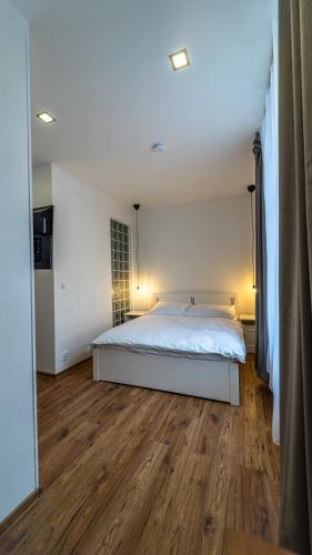 a bedroom with a white bed and a wooden floor at Hotel Cafe SokoLOVE in Sokolov