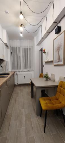a kitchen with a table and a yellow chair at Over the City in Oradea