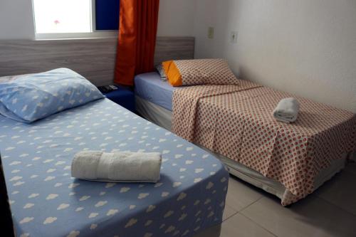 a room with two beds and a table with a pillow at Pousada Executiva SolRiso Aeroporto Florianópolis in Florianópolis