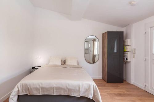 a white bedroom with a large bed and a mirror at Lumignons Lyonnais - Doua in Villeurbanne