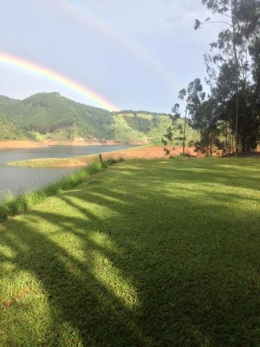 ein Regenbogen über einem Feld neben einem See in der Unterkunft Casa Tupa Recanto Familiar Pague 2 Minimo e fique 3 menos feriados in Natividade da Serra