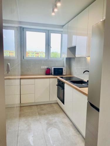 a kitchen with white cabinets and a sink and two windows at Apartament Świdnik in Świdnik