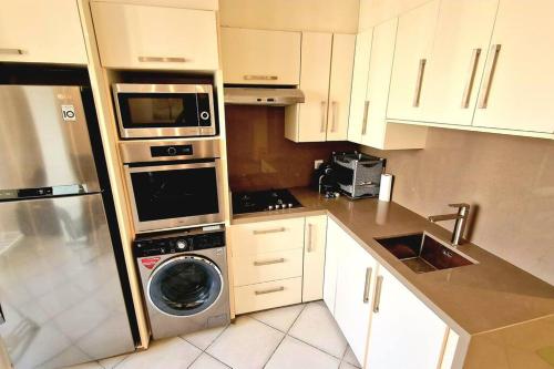 eine Küche mit einer Waschmaschine und einer Mikrowelle in der Unterkunft F2 haut-standing akid lotfi in Oran