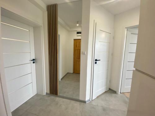 a hallway with white closet doors and a mirror at Apartament Świdnik in Świdnik