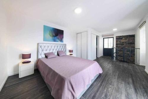 una camera da letto con un letto grande con una coperta viola di Lombo do Doutor Cottage 2 by Mth a Calheta