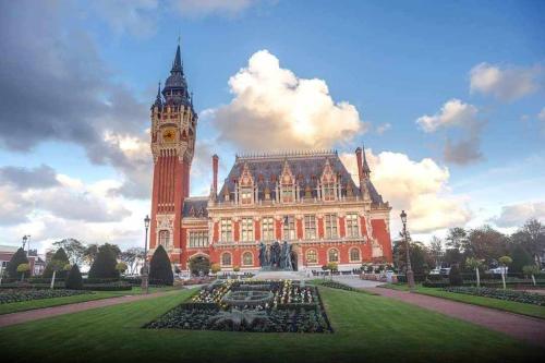 a large building with a clock tower in front of it at Appart proche plage Calais in Calais