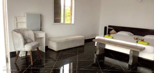 a bedroom with a bed and a chair and a mirror at Villa de luxe Domaine Léna vue sur mer in Foulpointe