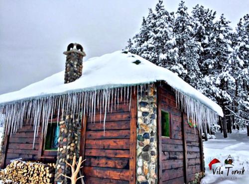 a cabin covered in snow with icicles on the roof at Vila Mali Tornik in Zlatibor