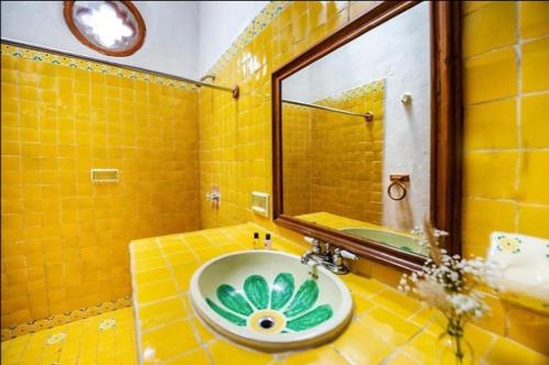 Baño amarillo con lavabo y espejo en Xani Mui en San Jerónimo Aculco