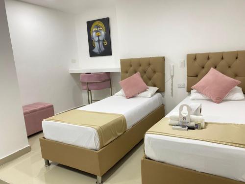 1 dormitorio con 2 camas y mesa. en Hotel Hernández CTG, en Cartagena de Indias