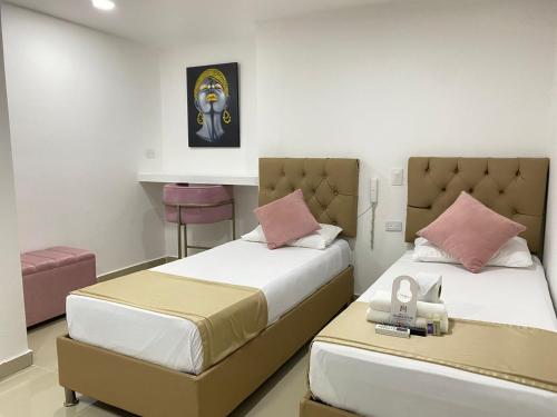 1 dormitorio con 2 camas y mesa. en Hotel Hernández CTG, en Cartagena de Indias